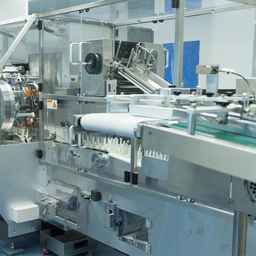 Close-up of high-speed industrial blister packaging machine or cartoning system processing products on a conveyor belt in a cleanroom environment