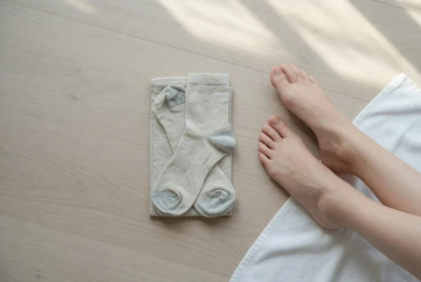 Person sitting with swollen ankles in summer heat, compression socks nearby